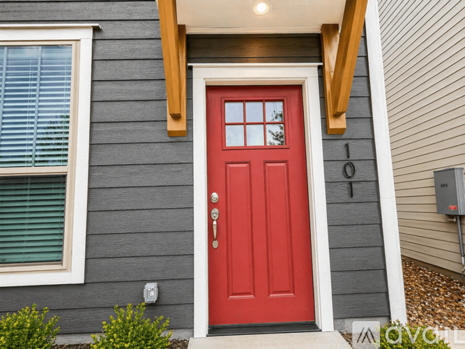 A red door is the centerpiece of this house's front entrance.