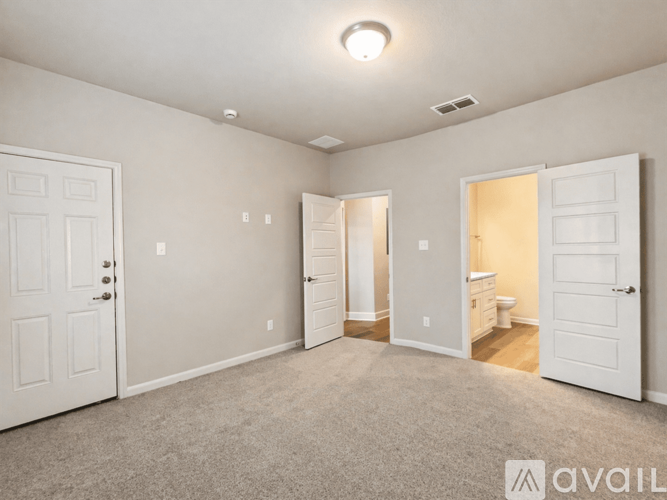 A spacious room with white doors and carpeted floor.