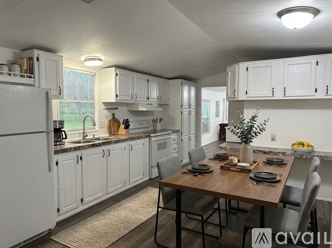 A kitchen with white cabinets and a wooden table set for a meal.
