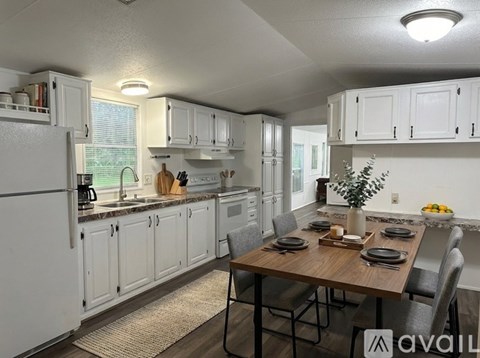 A kitchen with white cabinets and a wooden table set for a meal.
