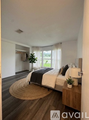 A bedroom with a bed, nightstand, and window with curtains.