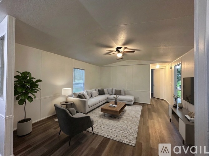 A living room with a white couch, a coffee table, and a ceiling fan.