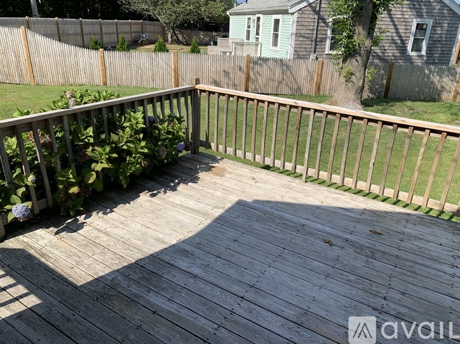 A wooden deck with a railing and a tree in the background.