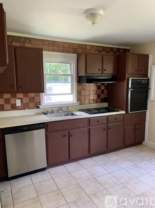 A kitchen with brown cabinets and a checkered backsplash.