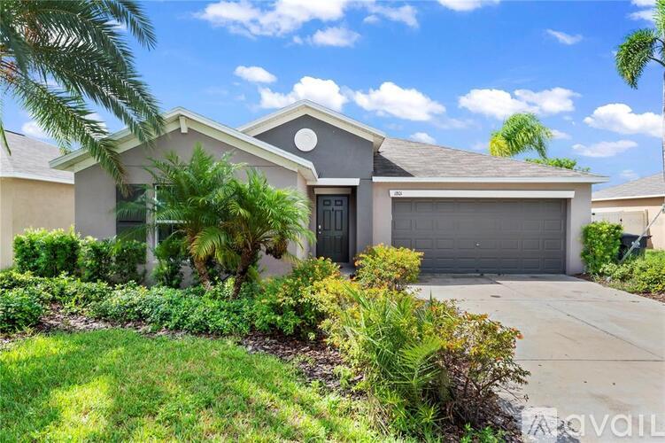 A house with a garage and a driveway surrounded by greenery.