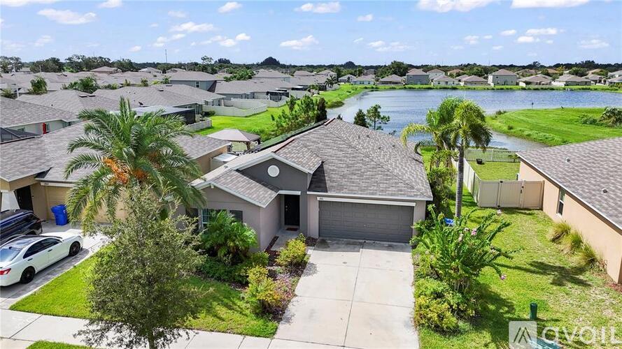A house with a car parked in front and a body of water in the background.