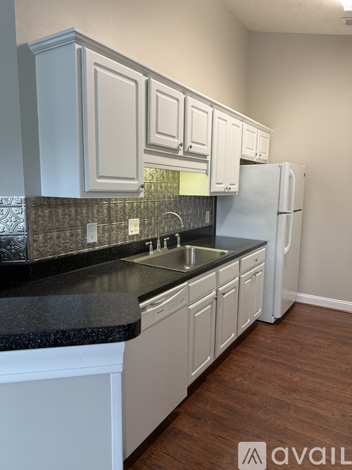 A kitchen with white cabinets and a black countertop.