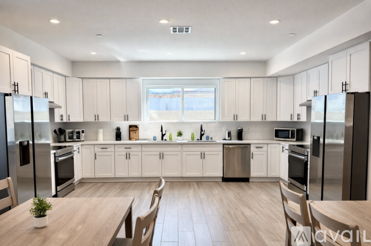 A modern kitchen with wooden floors and stainless steel appliances.