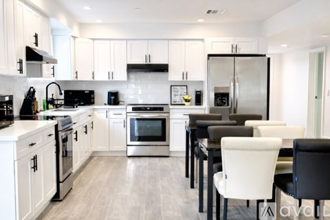 A modern kitchen with white cabinets and stainless steel appliances.