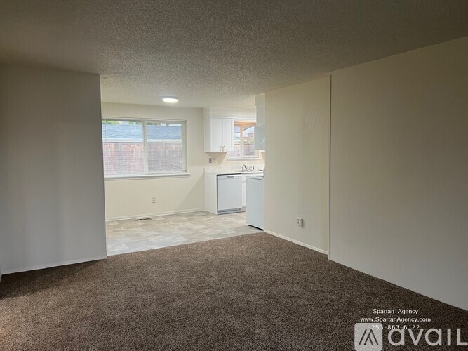 A room with a carpeted floor and a window with blinds.