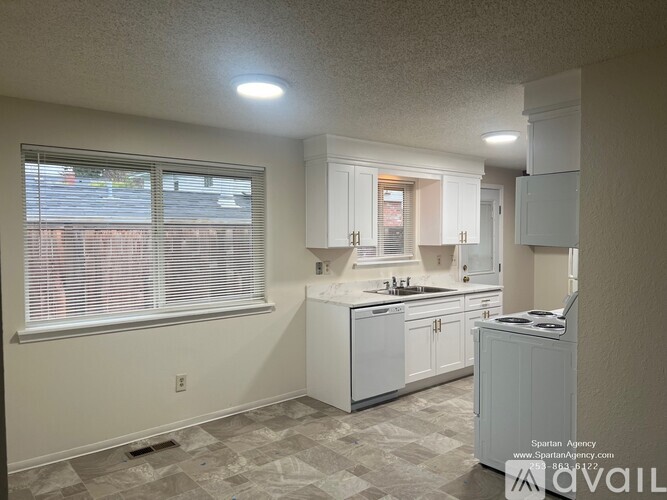A kitchen with white cabinets and a window with blinds.
