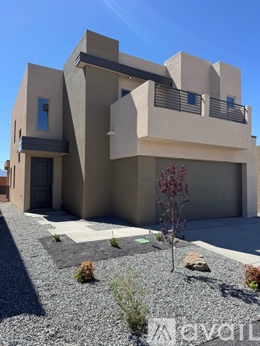 A modern house with a grey roof and a gravel driveway.