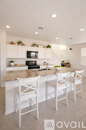 A kitchen with white chairs and a granite countertop.