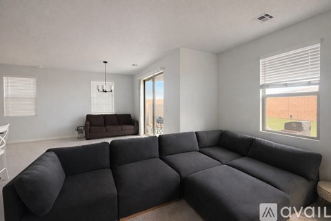 A living room with a large grey sectional sofa and a small brown ottoman.