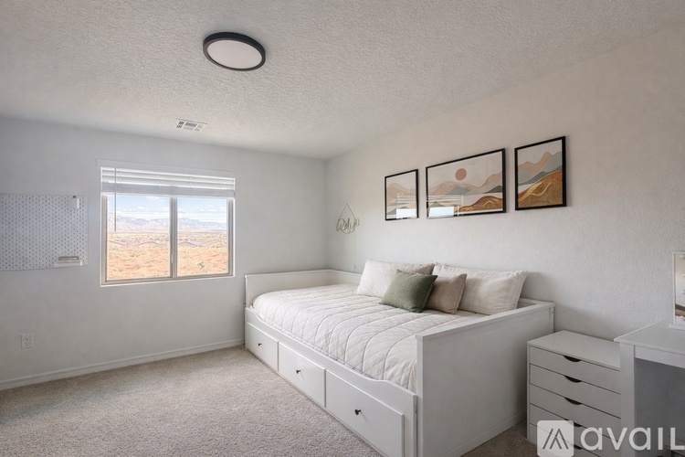 A bedroom with a large bed, a window with a view, and three pictures on the wall.