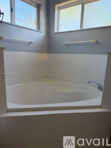 A white bathtub is in a bathroom with grey walls.