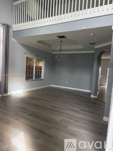 A spacious room with wooden flooring and a chandelier.