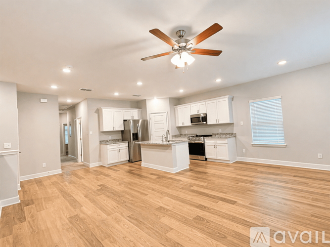 A spacious kitchen with a fan and wooden floors.