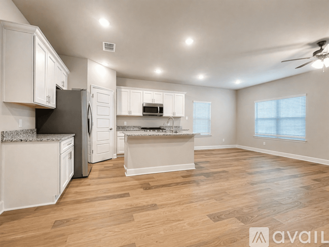 A spacious kitchen with white cabinets and a wooden floor.
