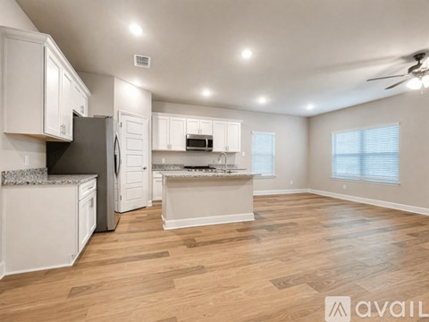 A spacious kitchen with white cabinets and a wooden floor.