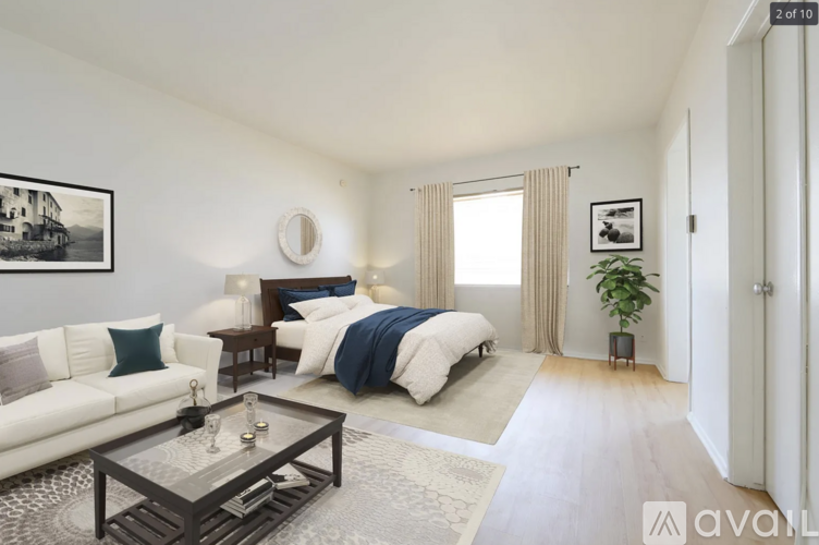 A well-lit bedroom with a large bed and a white couch.