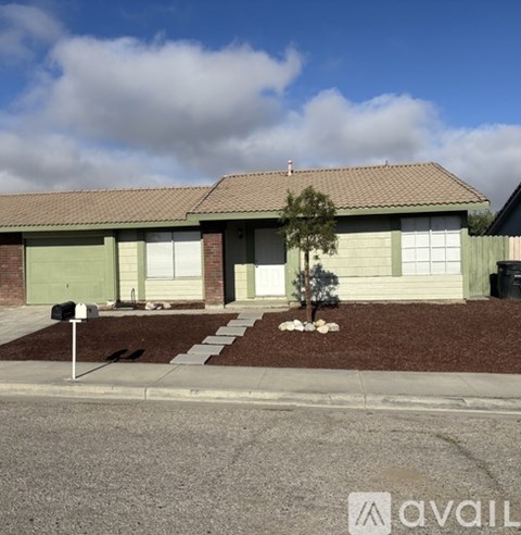 A house with a green garage door and a mailbox on the left.