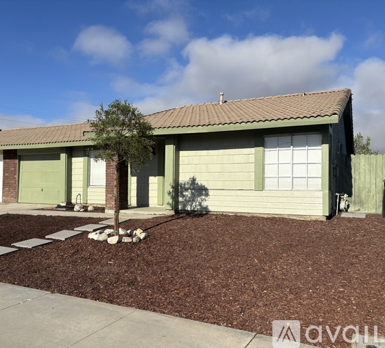 A house with a green garage door and a tree in front.