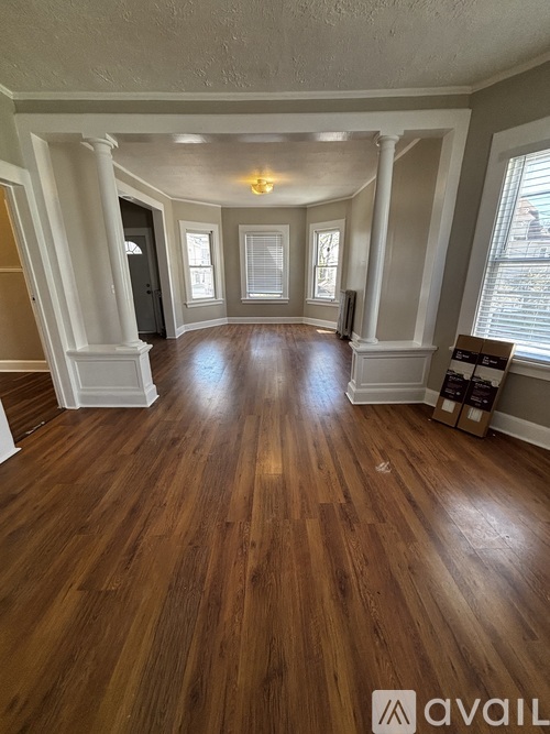A spacious room with wooden floors and white columns.