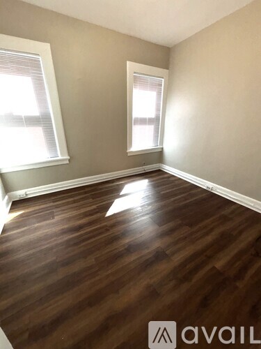 A room with wooden floors and two windows.