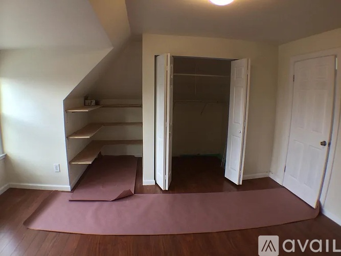 A room with a pink rug and a staircase.