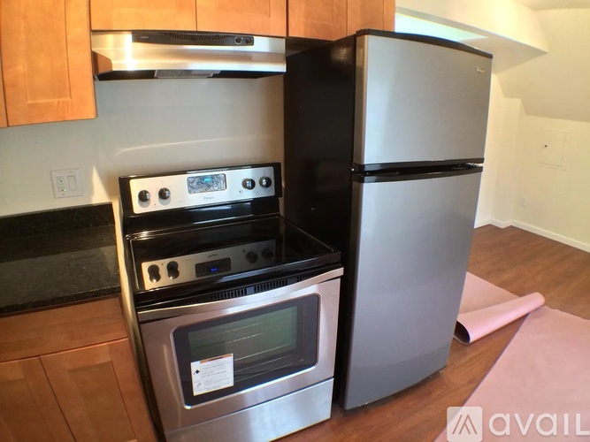 A black refrigerator stands next to a stove in a kitchen.