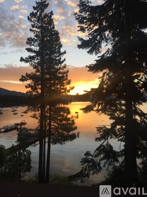 A beautiful sunset over a lake with trees in the foreground.