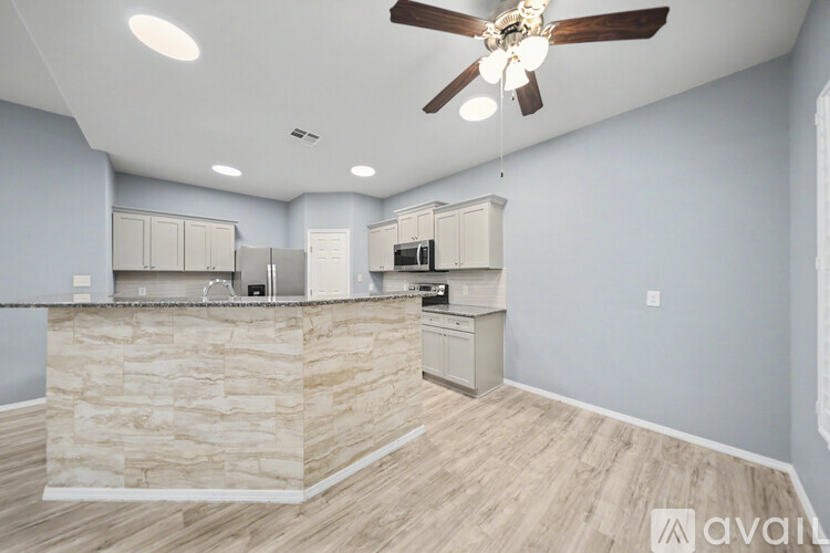 A kitchen with a stone counter and wooden flooring.
