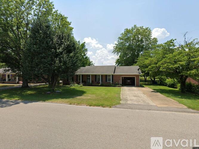 A house with a driveway and trees in front of it.