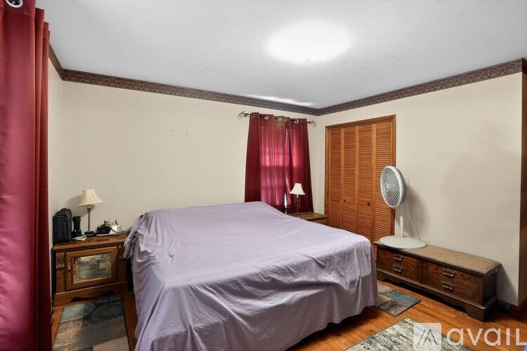 A bedroom with a bed, nightstand, and a fan.