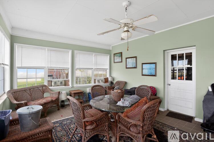 A living room with a glass table surrounded by chairs and a ceiling fan.