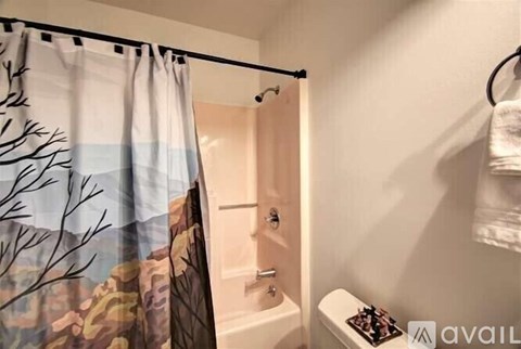 A bathroom with a shower curtain that has a tree design on it.