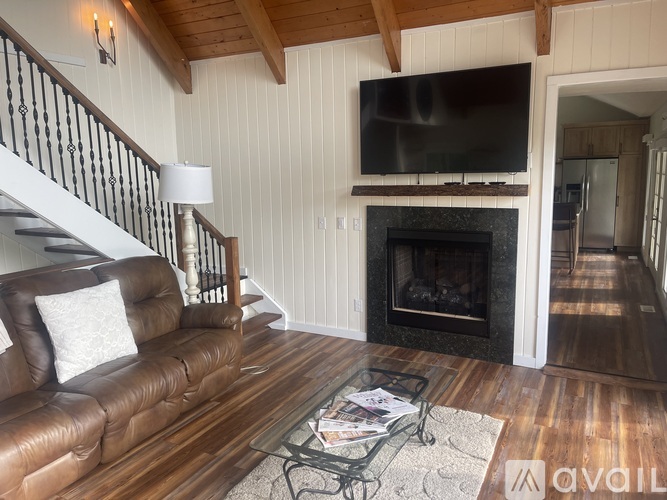 A living room with a brown leather couch and a fireplace.