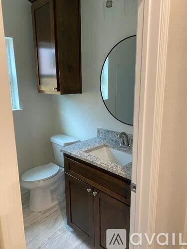 A bathroom with a toilet, sink and mirror.