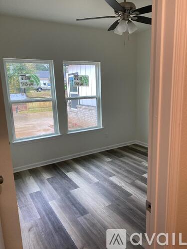 A room with a ceiling fan and two windows.