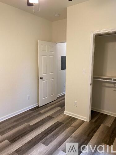 A room with a white door and wooden flooring.
