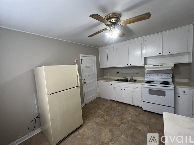 A kitchen with a refrigerator, stove, and cabinets.