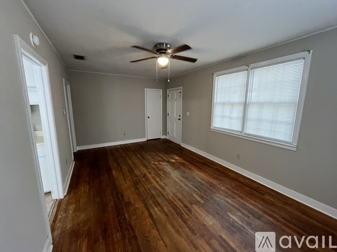 A room with a ceiling fan and wooden flooring.