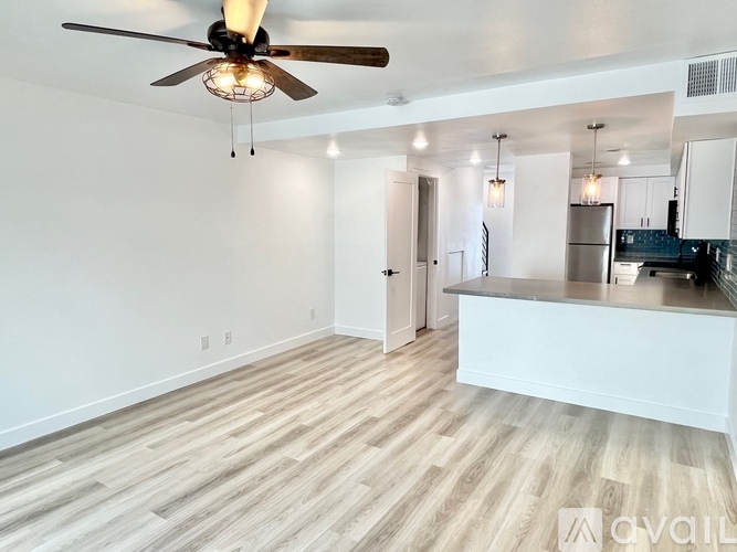 A spacious kitchen and living room with a ceiling fan and lighting fixtures.
