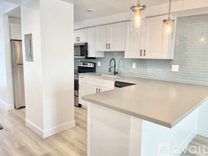 A kitchen with white cabinets and a light brown counter.