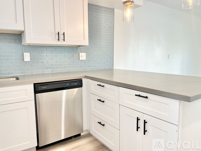A kitchen with white cabinets and a stainless steel dishwasher.