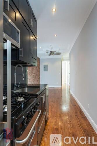 A modern kitchen with black cabinets and a wooden floor.