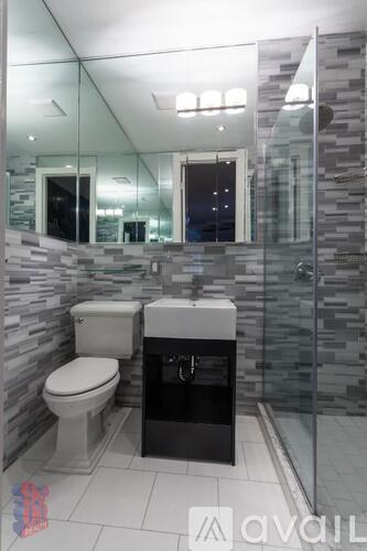 A modern bathroom with a toilet, sink, and glass shower stall.