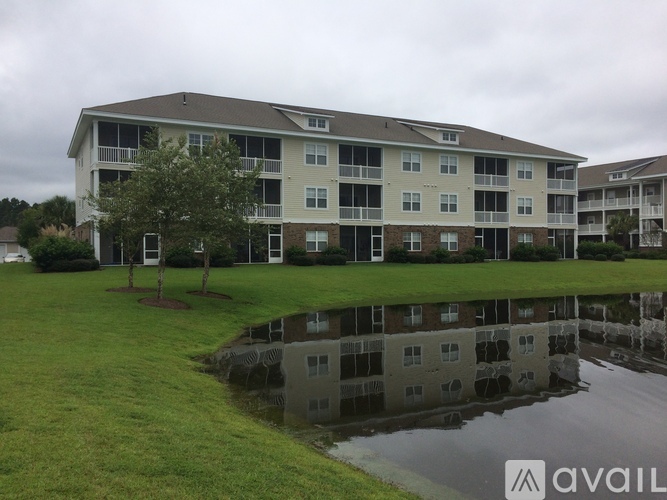A large apartment complex with a pond in front.