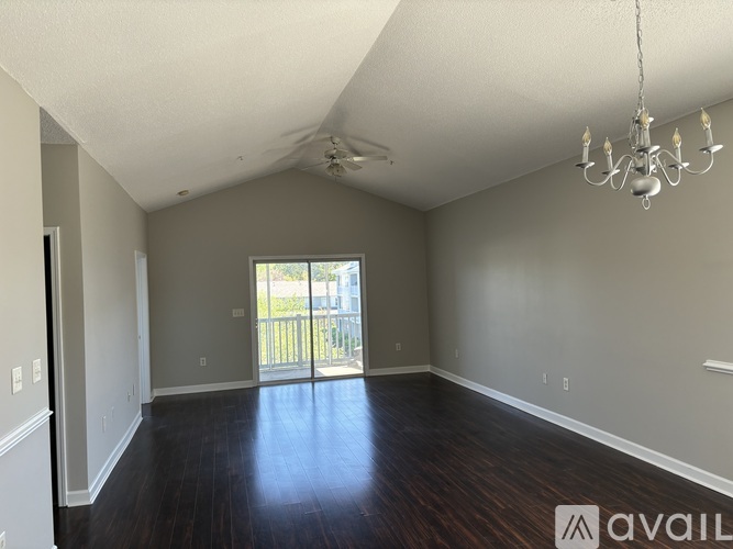 A room with a chandelier, sliding glass doors, and hardwood floors.
